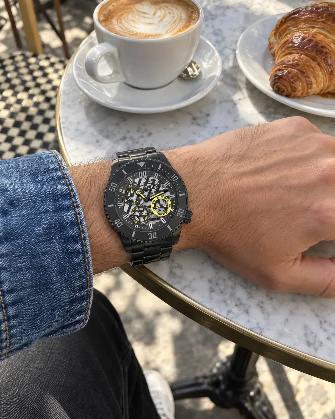 Montre Guess GW0488G3 homme portée au poignet, sur une table de café