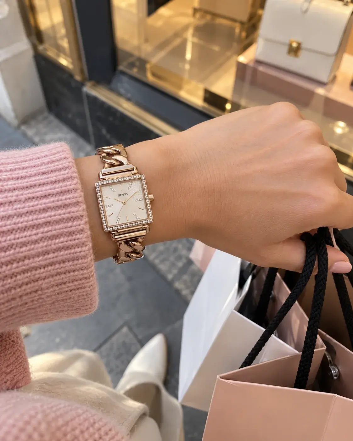 Montre Guess W1030L4 femme portée au poignet, devant une vitrine de boutique