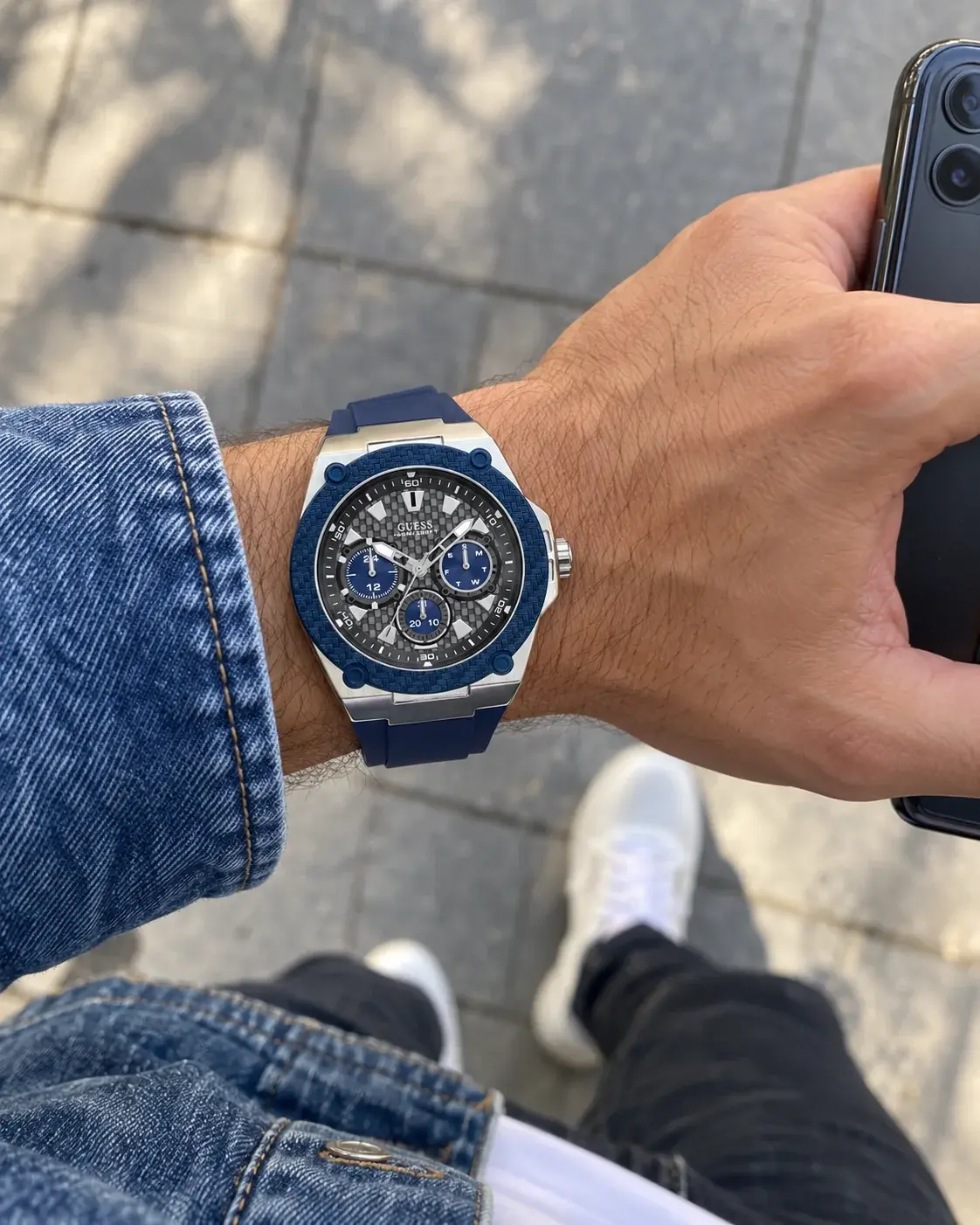 Montre Guess W1049G1 homme portée au poignet, avec un smartphone