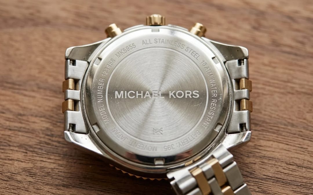 Verso view of the Michael Kors MK5955 case back with visible technical engravings: reference MK5955, water resistant, stainless steel