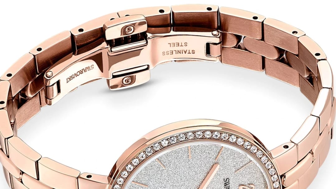 Gros plan du fermoir déployant gravé Swarovski et Stainless Steel sur le bracelet acier doré rose d'une montre Swarovski