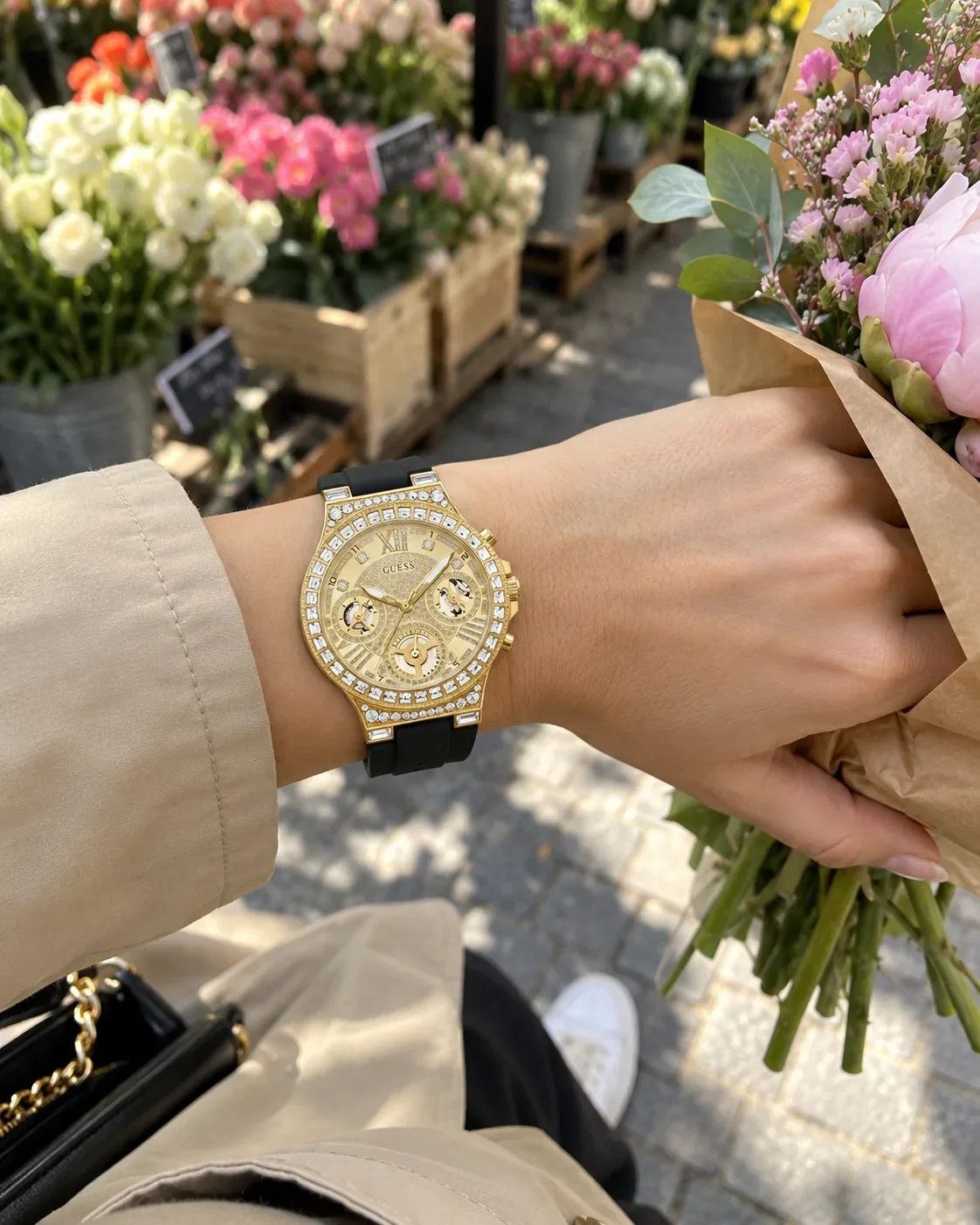 Montre Guess GW0257L1G femme portée au poignet, avec un bouquet au marché aux fleurs