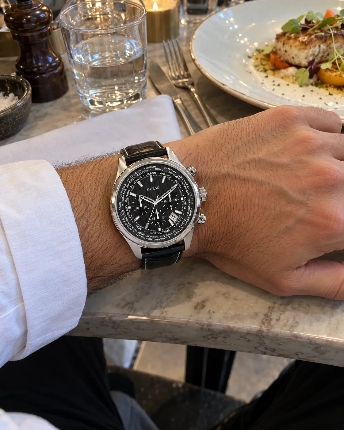 Montre Guess W0500G2 homme portée au poignet, sur une table de restaurant