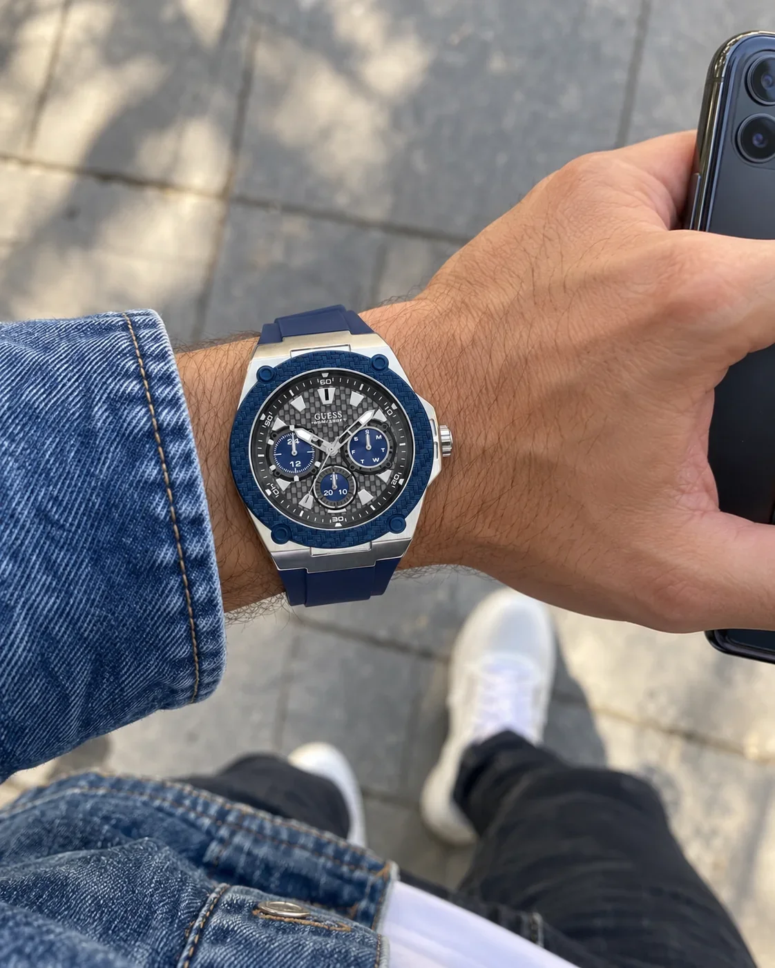 Montre Guess W1049G1 homme portée au poignet, avec un smartphone
