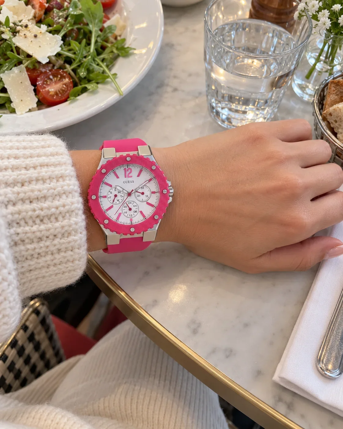 Montre Guess W90084L2 femme portée au poignet, sur une table de restaurant