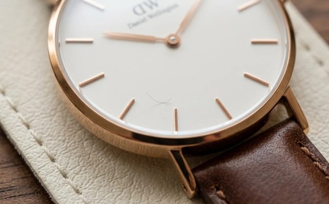 Macro of a watch dial in raking light revealing a tiny dust fibre under the crystal