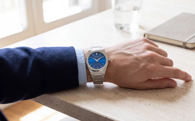Montre octogonale homme D1 Milano Ultra Thin UTBJ09 cadran bleu soleillé portée avec un blazer bleu marine, alternative accessible à la Royal Oak