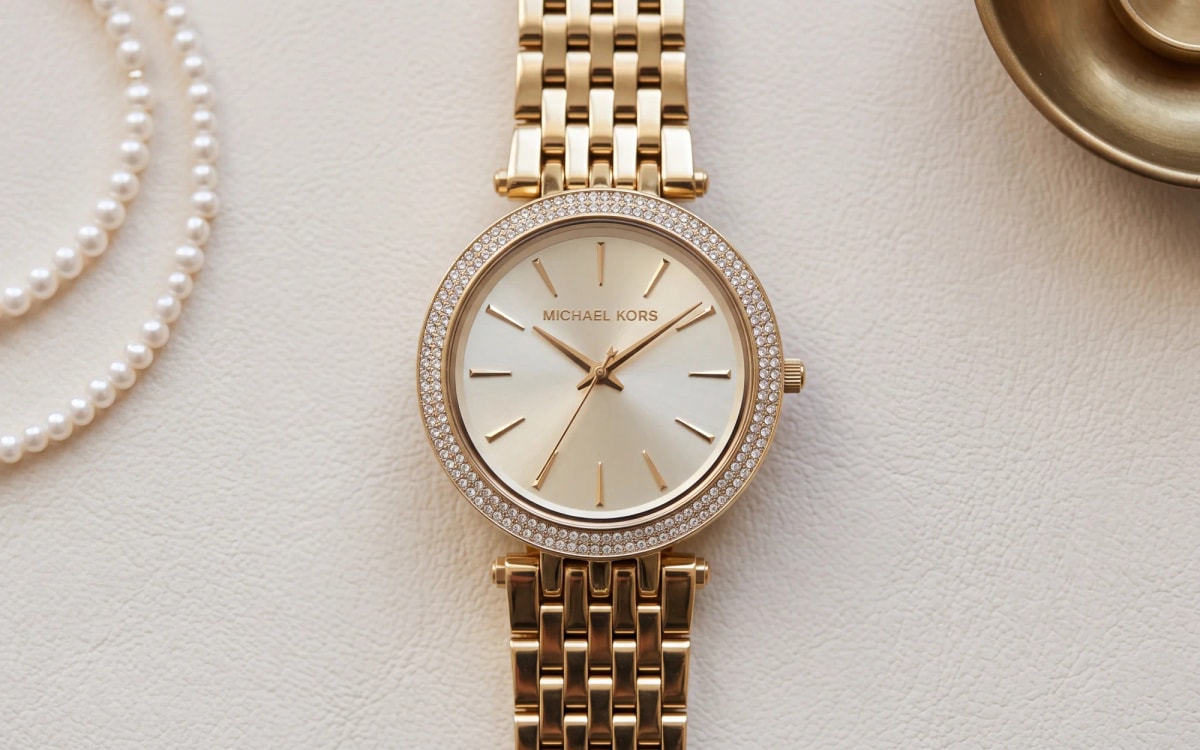 Michael Kors Darci MK3191 gold-tone watch with crystal pave bezel on ivory leather beside pearls