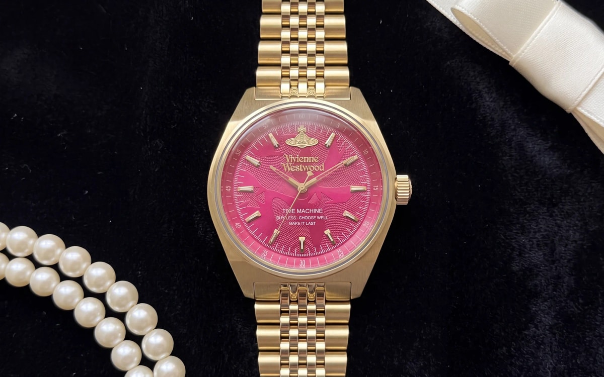 Montre Vivienne Westwood Lady Sydenham VV251RRGD dorée à cadran fuchsia, posée sur velours noir avec des perles