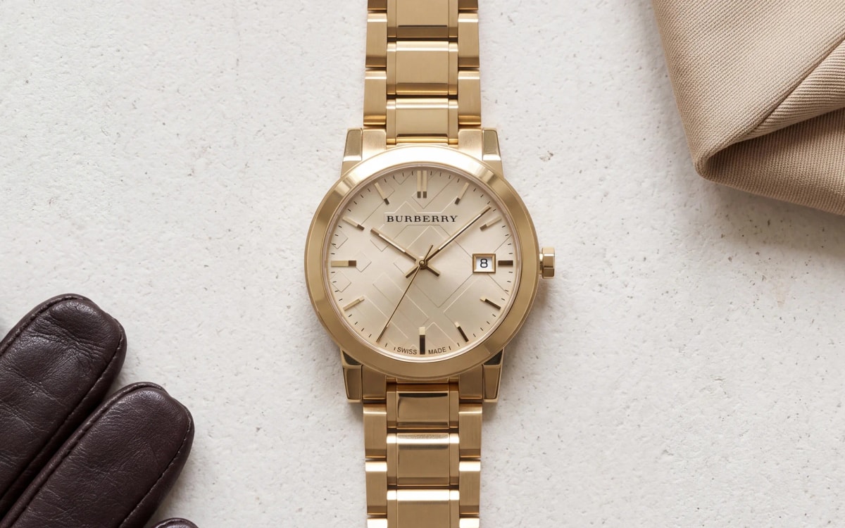 Montre femme Burberry The City BU9033 en or jaune, bracelet doré, posée sur de la pierre de Portland