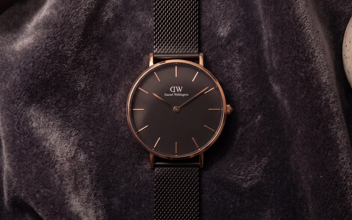 Montre Daniel Wellington Classic Petite Ashfield or rose, cadran noir et maille noire, sur velours gris à la lampe