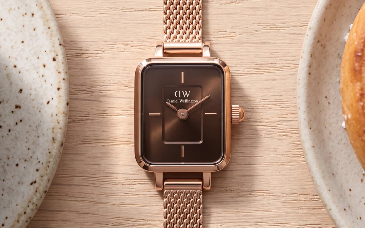 Montre Daniel Wellington Quadro Mini or rose, cadran chocolat, posée sur bois blond entre un café et une kanelbulle