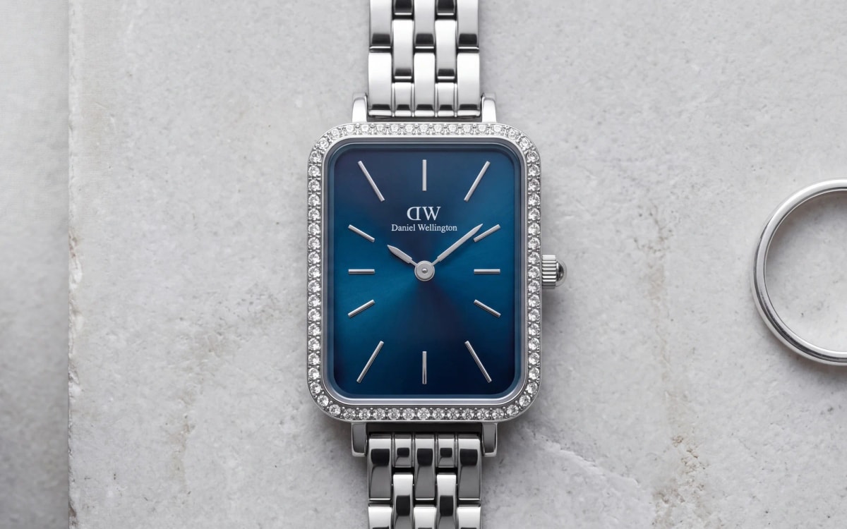 Montre Daniel Wellington Quadro en acier à lunette sertie, cadran bleu arctique, sur pierre grise avec une bague argent