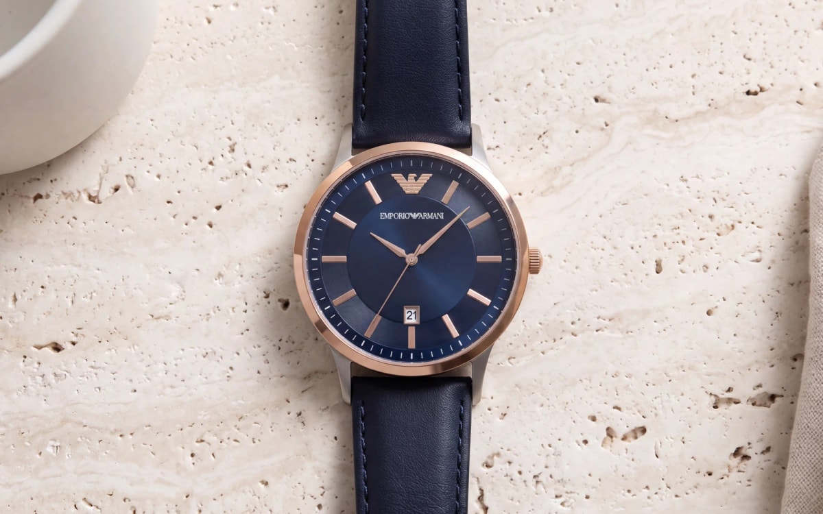 Montre homme Emporio Armani Renato AR11188, lunette or rose et cadran bleu nuit, cuir bleu, sur du travertin