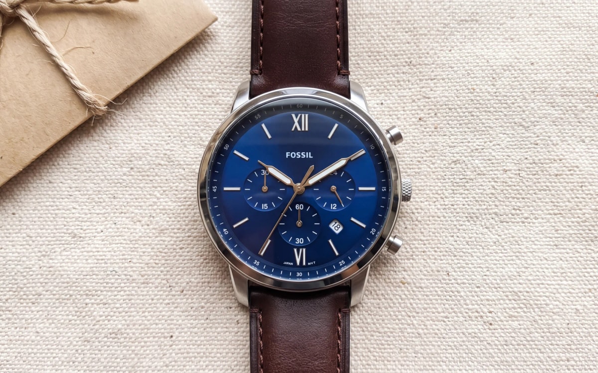 Montre homme Fossil Neutra FS6018, chronographe cadran bleu sur cuir marron, posé sur toile près d'une enveloppe