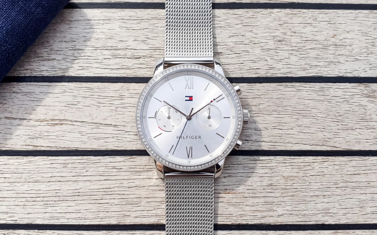 Montre femme Tommy Hilfiger 1782301 en acier, lunette sertie et cadran argenté, maille milanaise sur un pont en teck