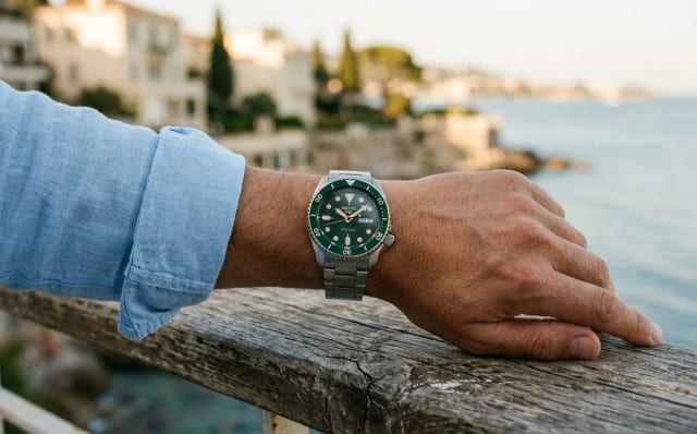 Montre style Rolex Submariner : Seiko 5 Sports SRPD63K1 automatique cadran et lunette verts portée au poignet en extérieur